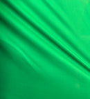 Solid mint green rayon challis fabric draped in soft, spiral folds. 