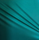 Solid teal rayon challis fabric draped in soft, spiral folds. 
