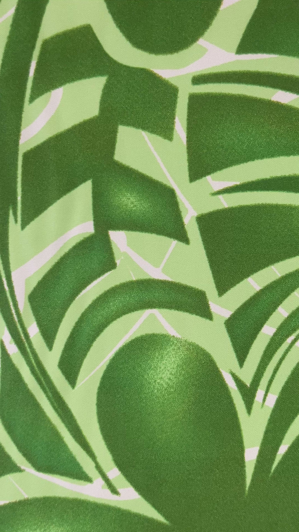 A close-up video showcasing a green and white polyester fabric featuring a tropical Monstera leaf pattern. The camera pans across the textile, highlighting the vibrant lime and forest green tones of the botanical print and the smooth, woven texture of the fabric.